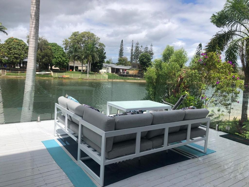 Un sofá sentado en una terraza junto a un lago. en Waterfront 3 Bedroom House in Family Friendly Resort, en Gold Coast