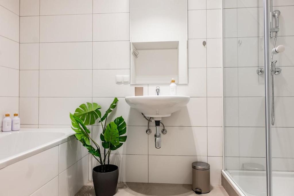 a white bathroom with a sink and a potted plant at Fast Wifi I 4 min to U3 Zipperer Straße in Vienna