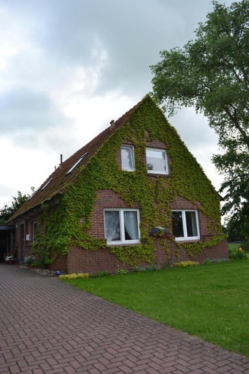 a brick house covered in ivy with two windows at Inselhof Steengrafe - Strandblick in Schwanewede