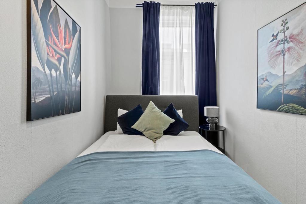 a bedroom with a bed with blue curtains and a window at Fast Wifi I 4 min to U3 Zipperer Straße in Vienna