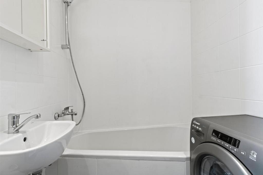 a bathroom with a washing machine and a sink at Fast Wifi I 4 min to U3 Zipperer Straße in Vienna