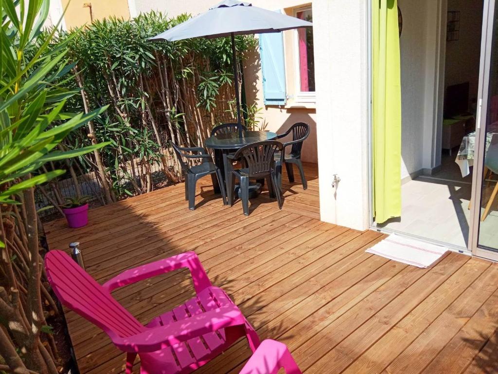 un patio avec une table, des chaises et un parasol dans l'établissement Le Lagon Bleu - Fidji 12 - Rez de jardin privatif - Tennis - Piscine, à Fréjus