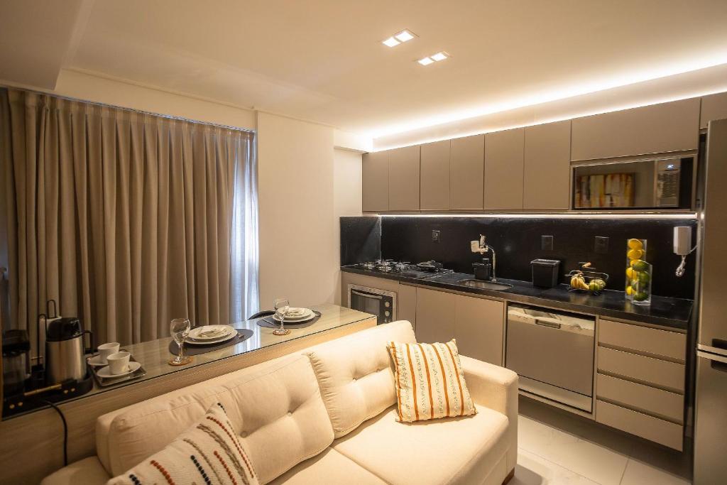 a living room with a white couch and a kitchen at Move #914 - Apartamento Confortável by Carpediem in Tambaú