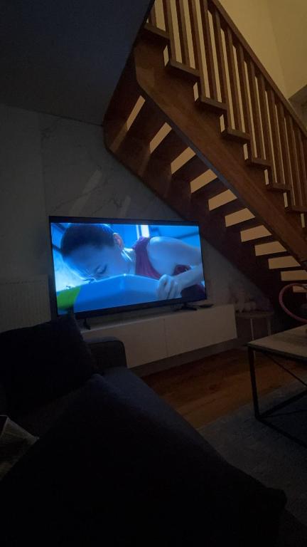 sala de estar con TV y escalera en Apartman Kenan, en Bjelašnica