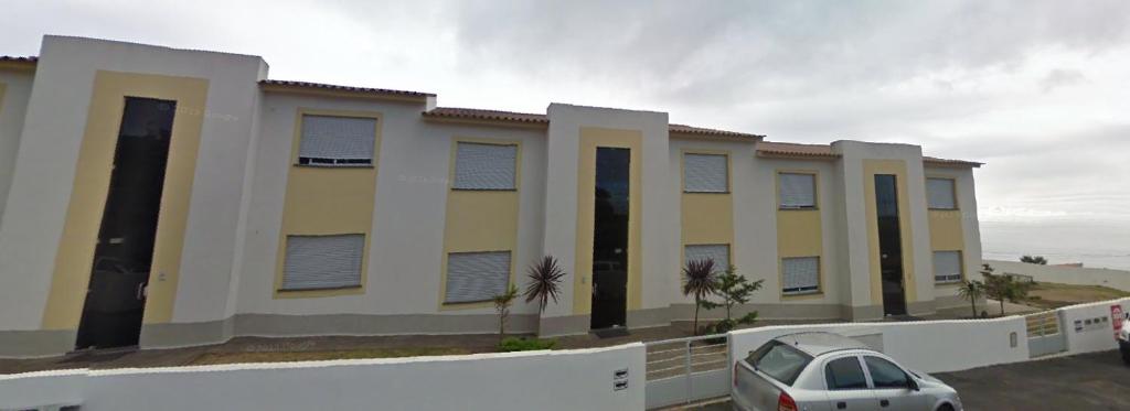 a building with a car parked in a parking lot at Alojamento Luna in Porto Judeu