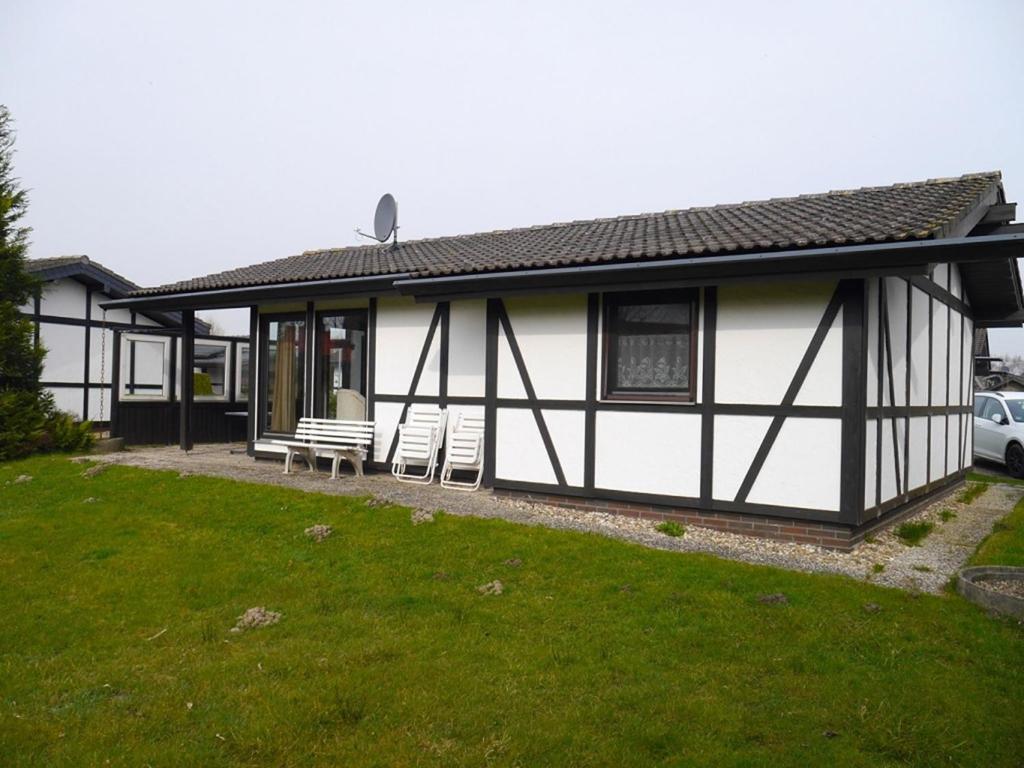 a white and black house with two chairs and a yard at Bungalow M 43 in Burhave in Burhave