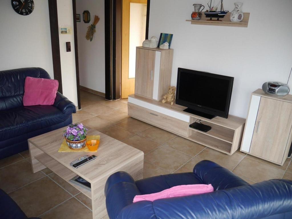 a living room with a couch and a tv at Bungalow M 07 in Burhave in Burhave