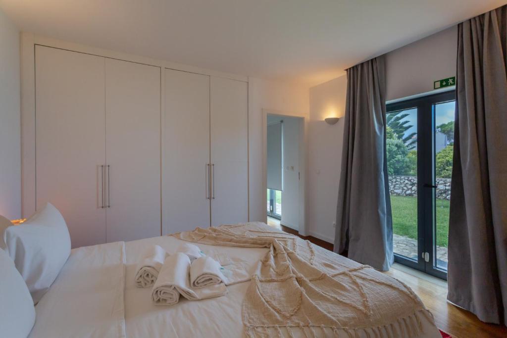 a bedroom with a bed with towels on it at Penedo Escape Sea Suites in Colares