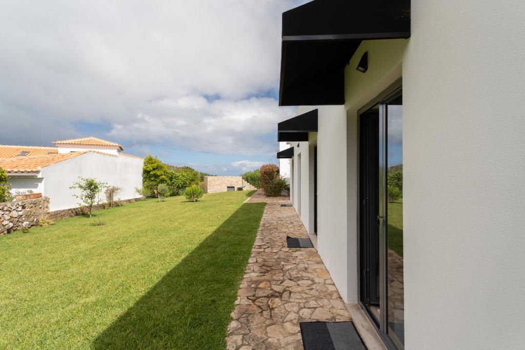 an external view of a house with a grass yard at Penedo Escape Sea Suites in Colares