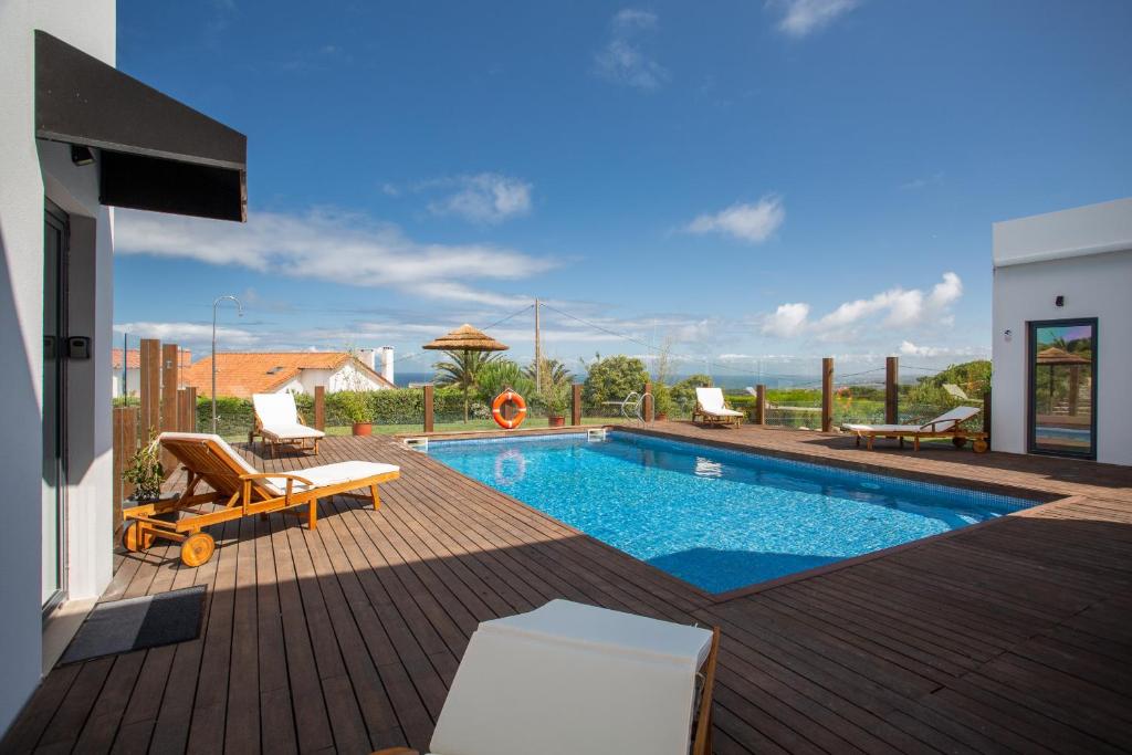 a backyard with a swimming pool and a wooden deck at Penedo Escape Sea Suites in Colares
