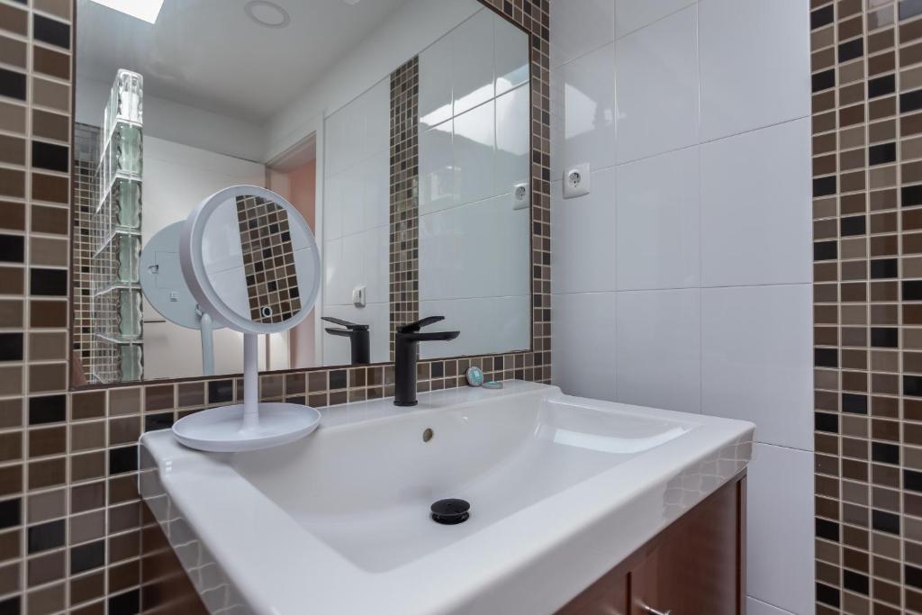 a bathroom with a white sink and a mirror at Penedo Escape Sea Suites in Colares