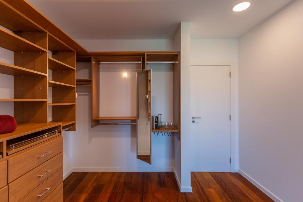 a kitchen with white walls and wooden cabinets at Penedo Escape Sea Suites in Colares