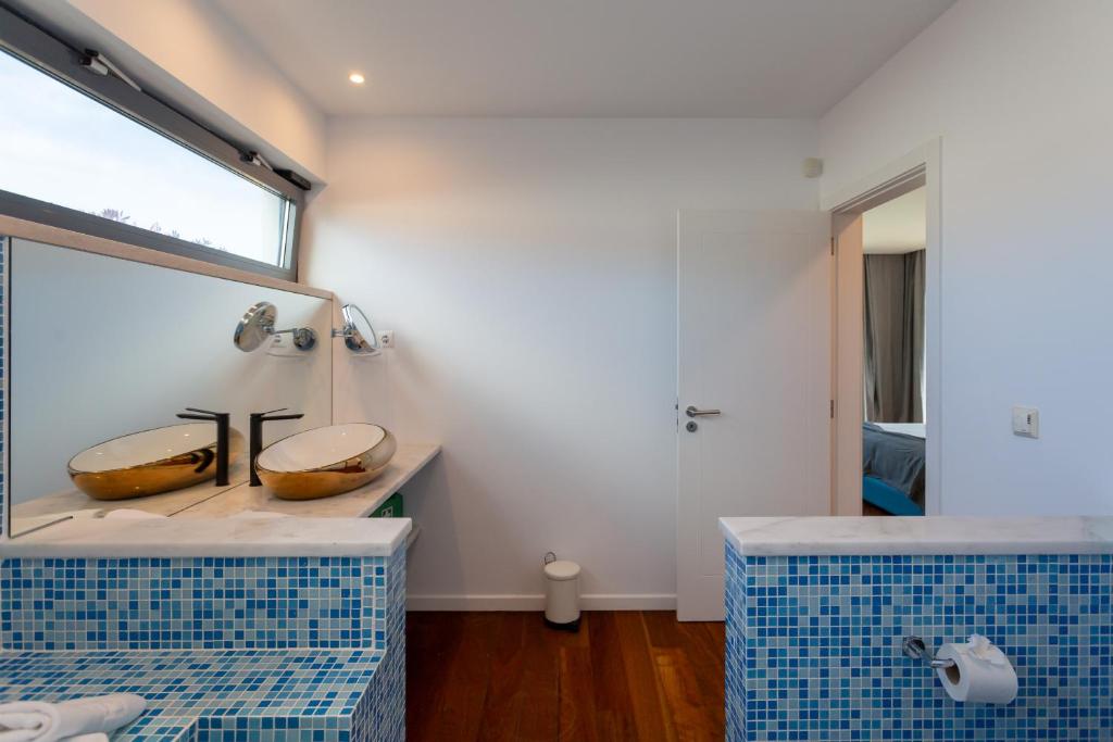 a bathroom with two sinks and a mirror at Penedo Escape Sea Suites in Colares