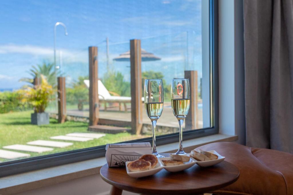two glasses of wine on a table next to a window at Penedo Escape Sea Suites in Colares