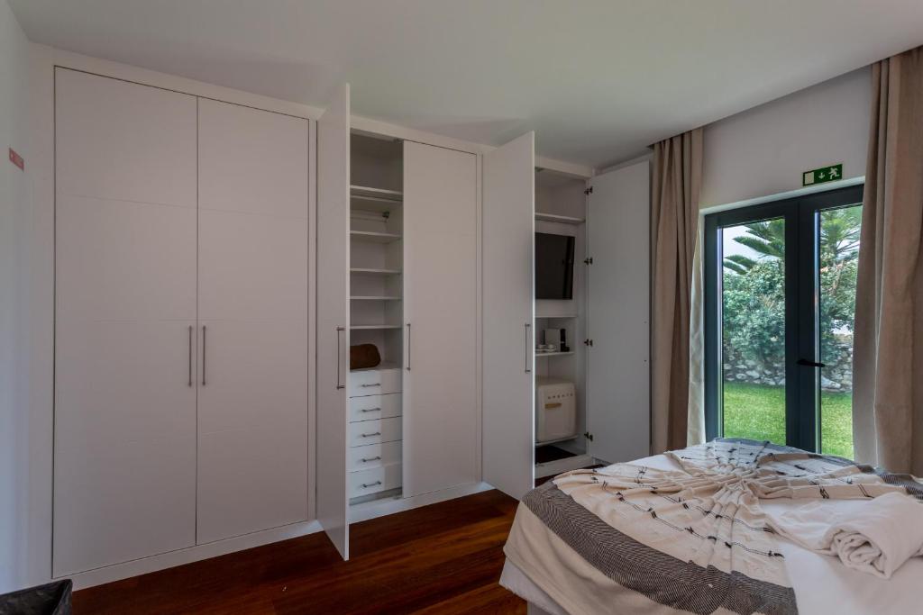 a bedroom with white cabinets and a bed at Penedo Escape Sea Suites in Colares
