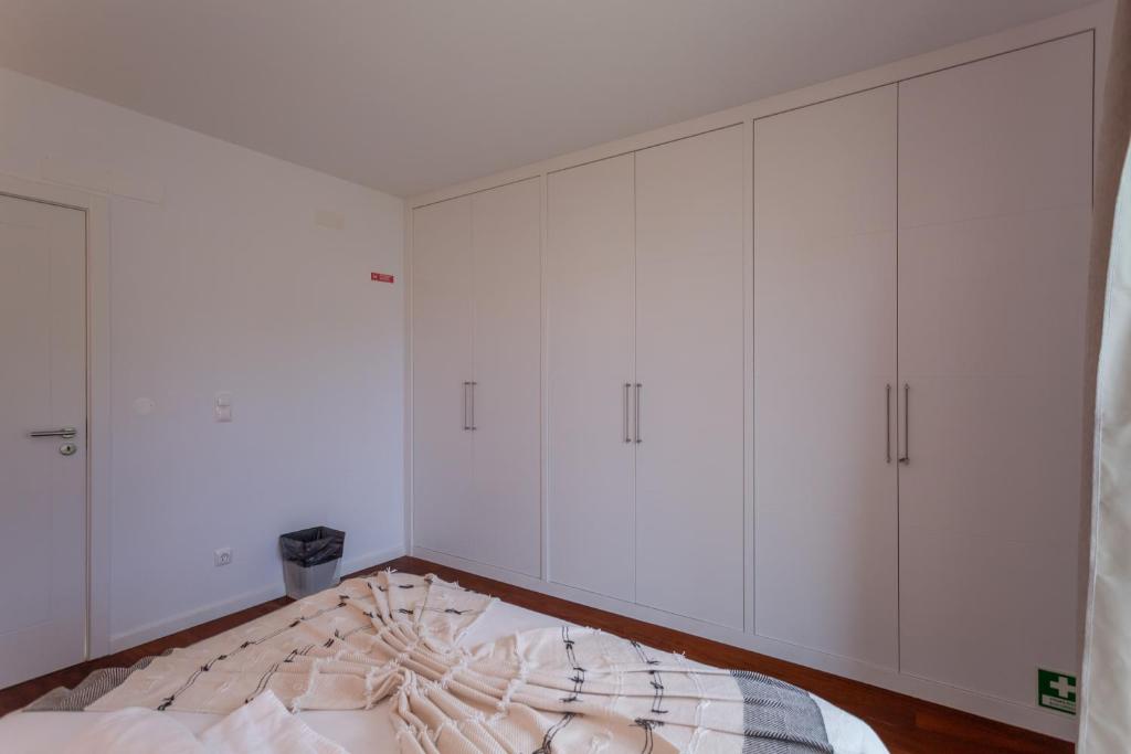 a bedroom with white cabinets and a bed at Penedo Escape Sea Suites in Colares
