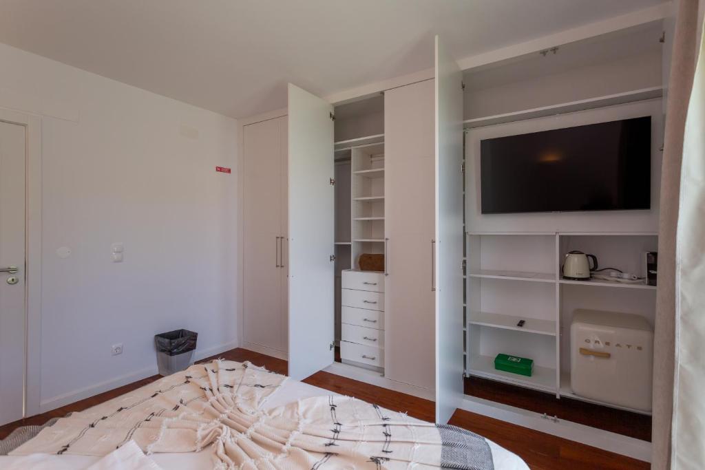 a bedroom with a bed and a flat screen tv at Penedo Escape Sea Suites in Colares
