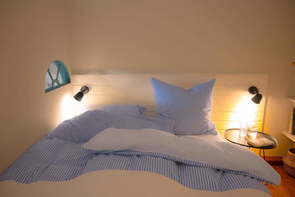 a bed with blue and white striped sheets and pillows at Windhauch in Westermarkelsdorf