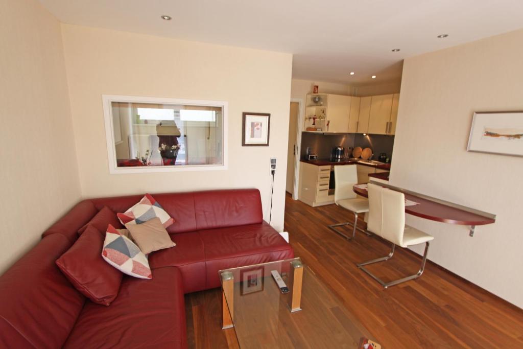 een woonkamer met een rode bank en een keuken bij Strandidyll, 54 - Typ A1 in Grömitz