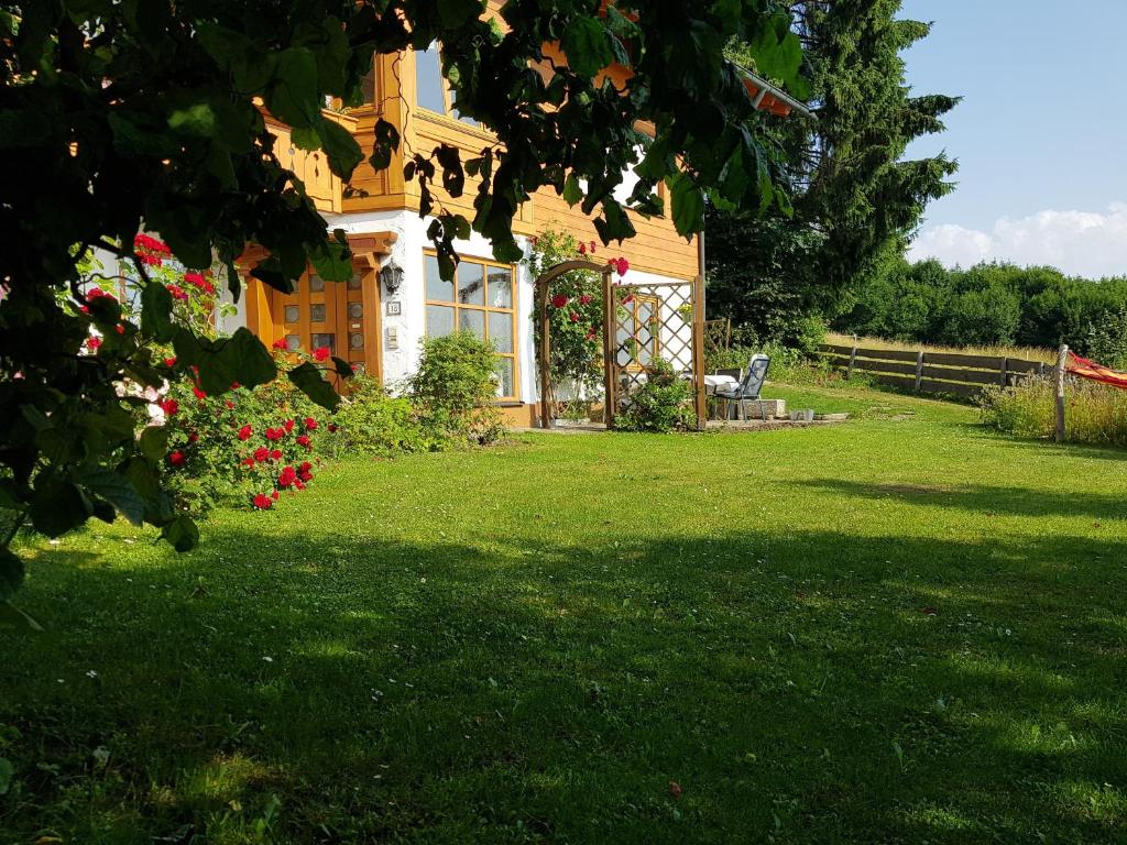 a yellow house with a yard with green grass and flowers at Ferienwohnung Schloßberg 2 in Peiting