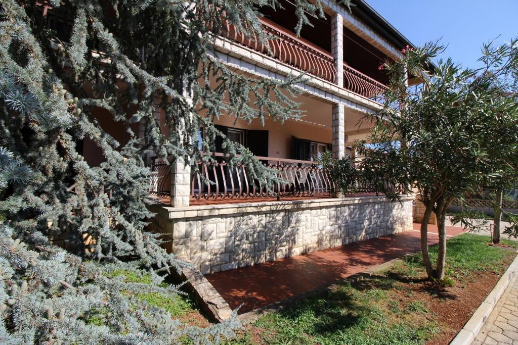 dom z płotem i drzewami przed nim w obiekcie Ferienwohnung Rosmarin Porec w Poreču
