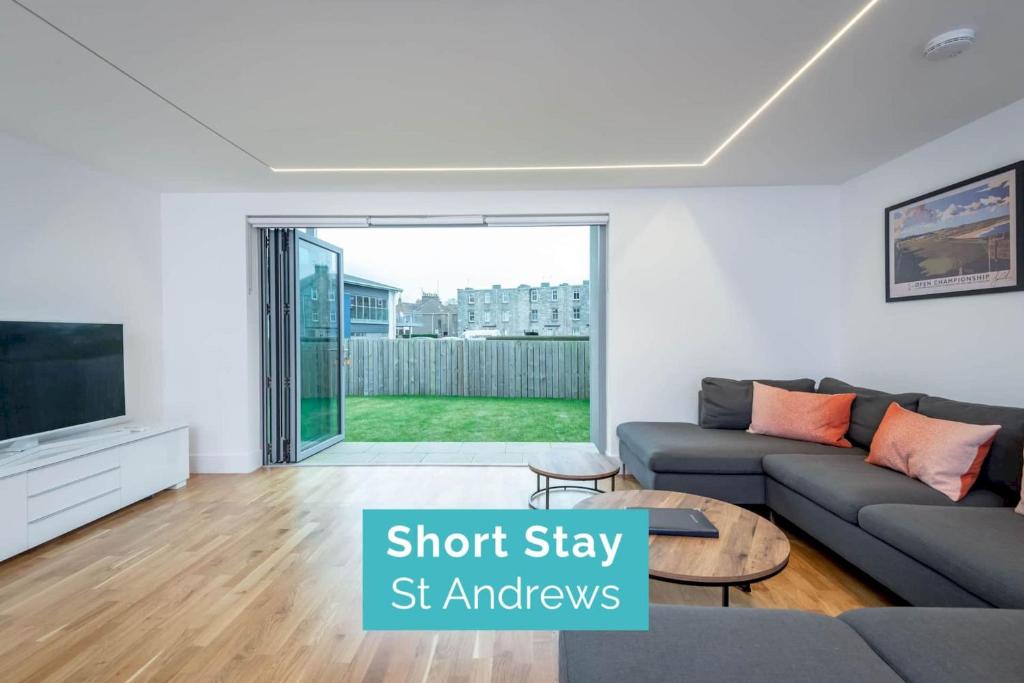 a living room with a couch and a tv at Square Green - No 12 Garden in St. Andrews