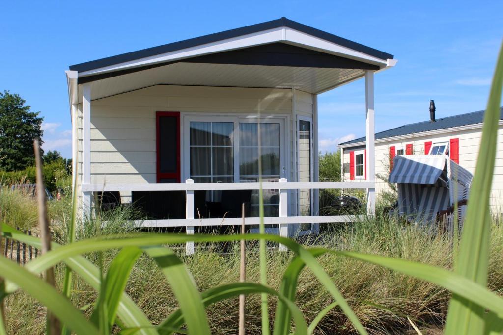 een tiny house met een veranda in het gras bij Pier98 19 in Scharbeutz