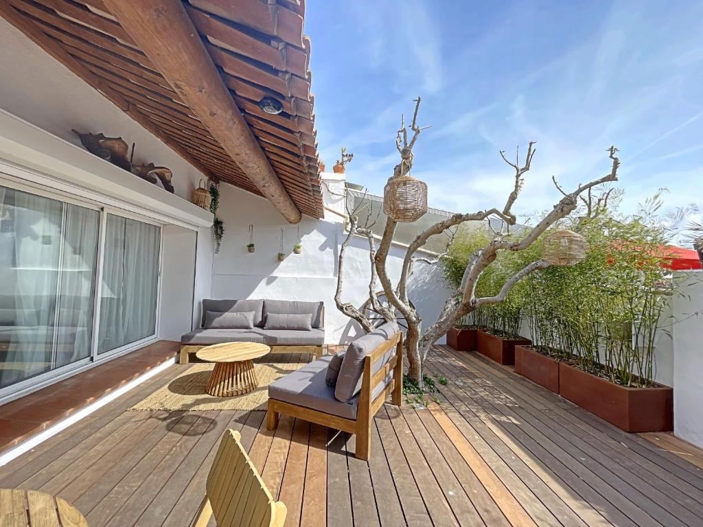 une terrasse en bois avec un arbre sur une maison dans l'établissement Maison de village climatisée pour 4 pers aux Saintes-Maries-de-la-Mer - FR-1-475-183, à Saintes-Maries-de-la-Mer