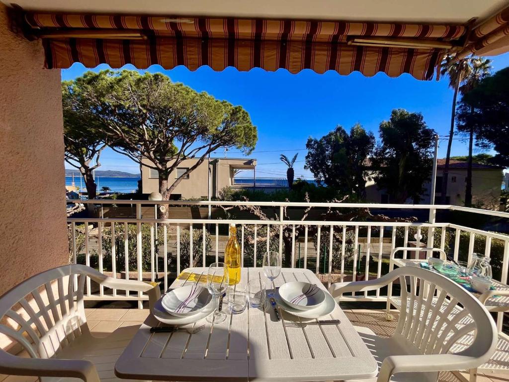 - une table et des chaises blanches sur une terrasse avec vue sur l'océan dans l'établissement Studio climatisé avec parking face à la mer - 2 couchages - FR-1-226B-233, à Cavalaire-sur-Mer
