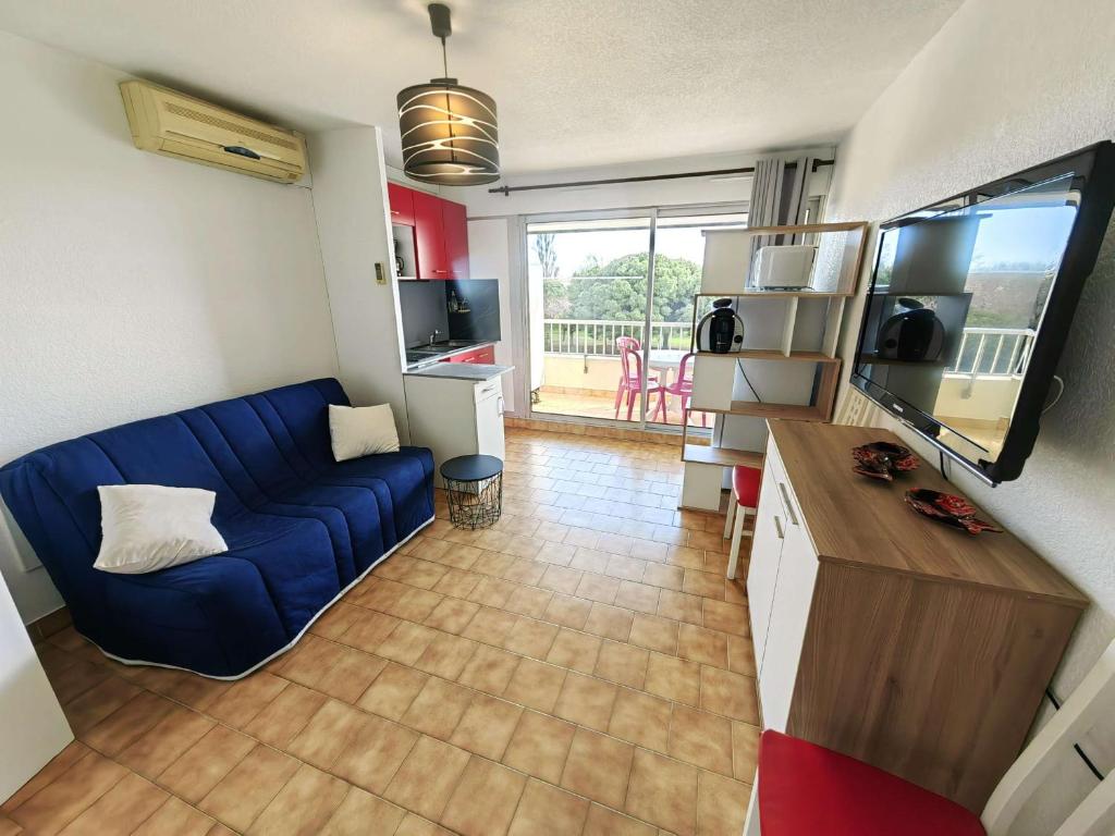 un salon avec un canapé bleu et une cuisine dans l'établissement Studio cabine climatisé pour 4, piscine, Cap d'Agde - FR-1-607-209, au Cap d'Agde