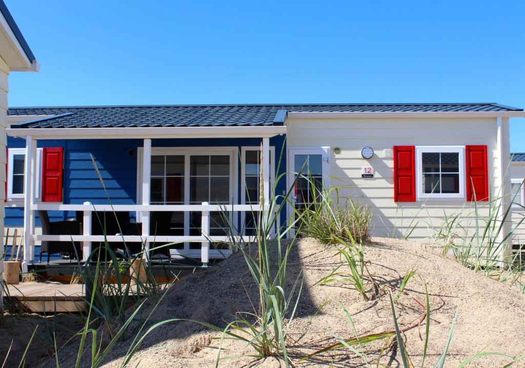 a small house with red doors on a beach at Strand 15 in Scharbeutz