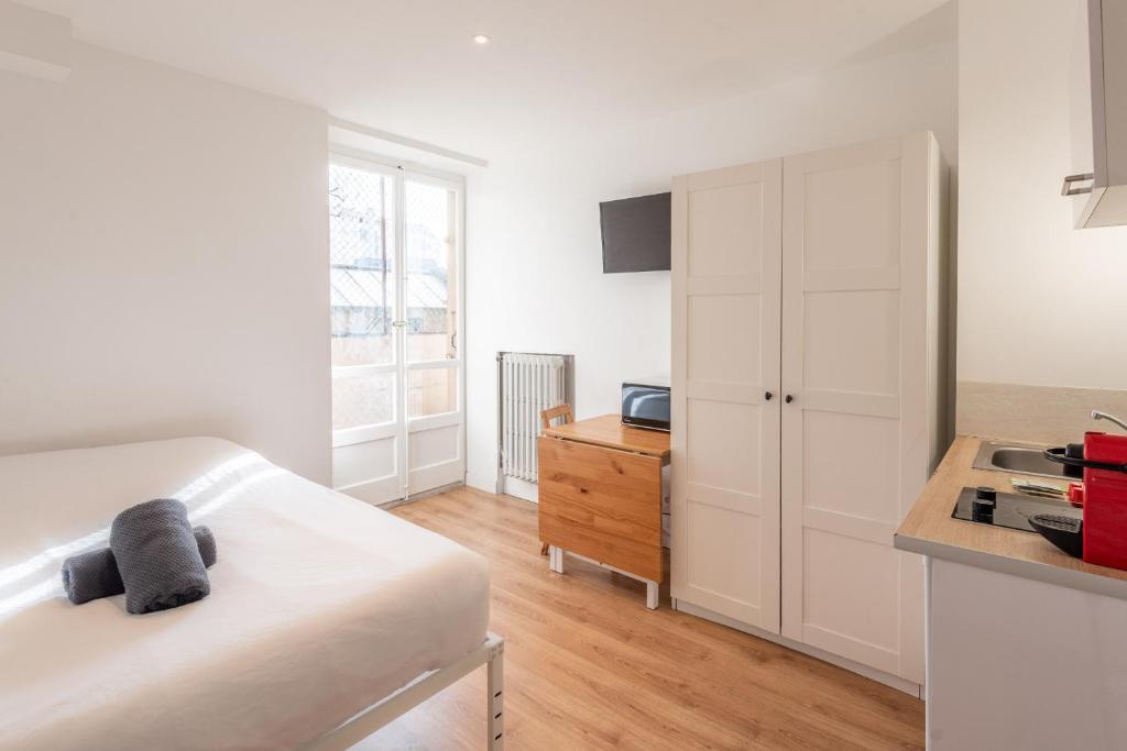 - une chambre blanche avec un lit et une armoire en bois dans l'établissement M22 studio avec balcon proche de la gare, à Annemasse