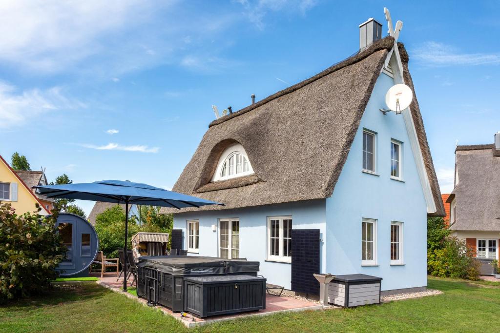 a white house with a thatched roof with a grill at C 5 Premium Reethaus Delphin mit eigenem Whirlpool und Außensauna in Gramkow