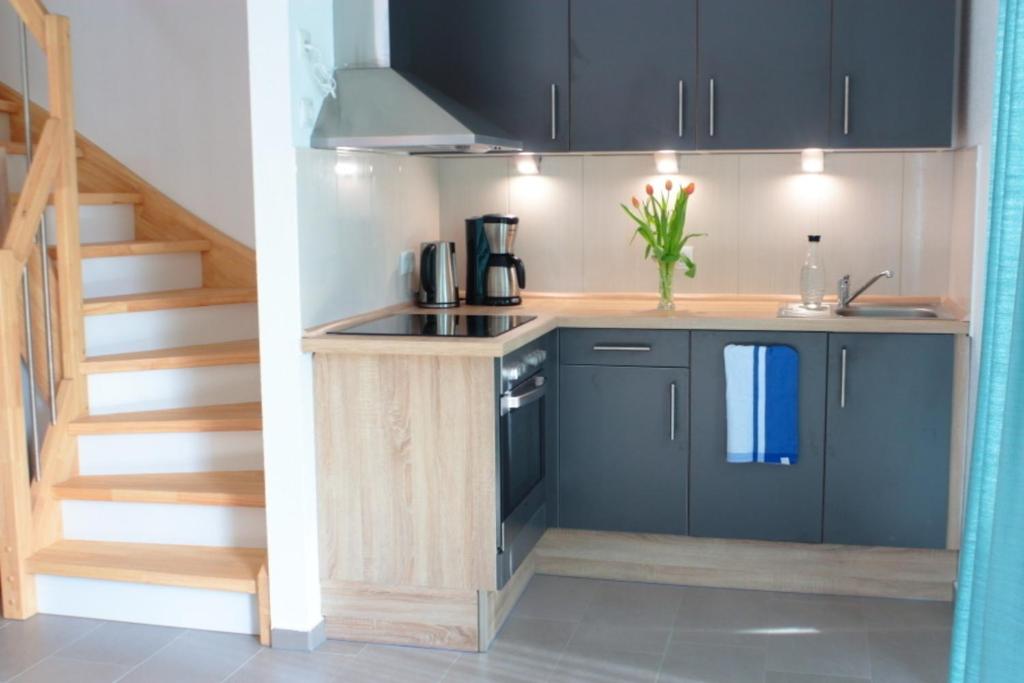 StickHaus 4711 rechtes Haus in Tossens的一间设有黑色橱柜和楼梯的小厨房