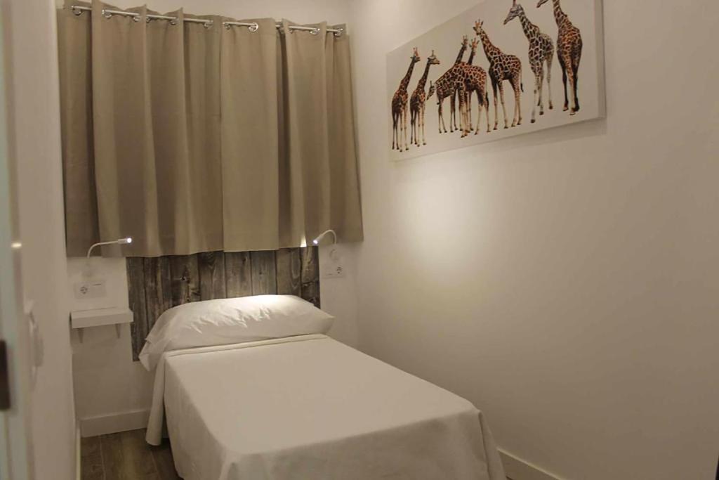 sypialnia z łóżkiem i zdjęciem żyraf w obiekcie Hostal royal begoña w Madrycie