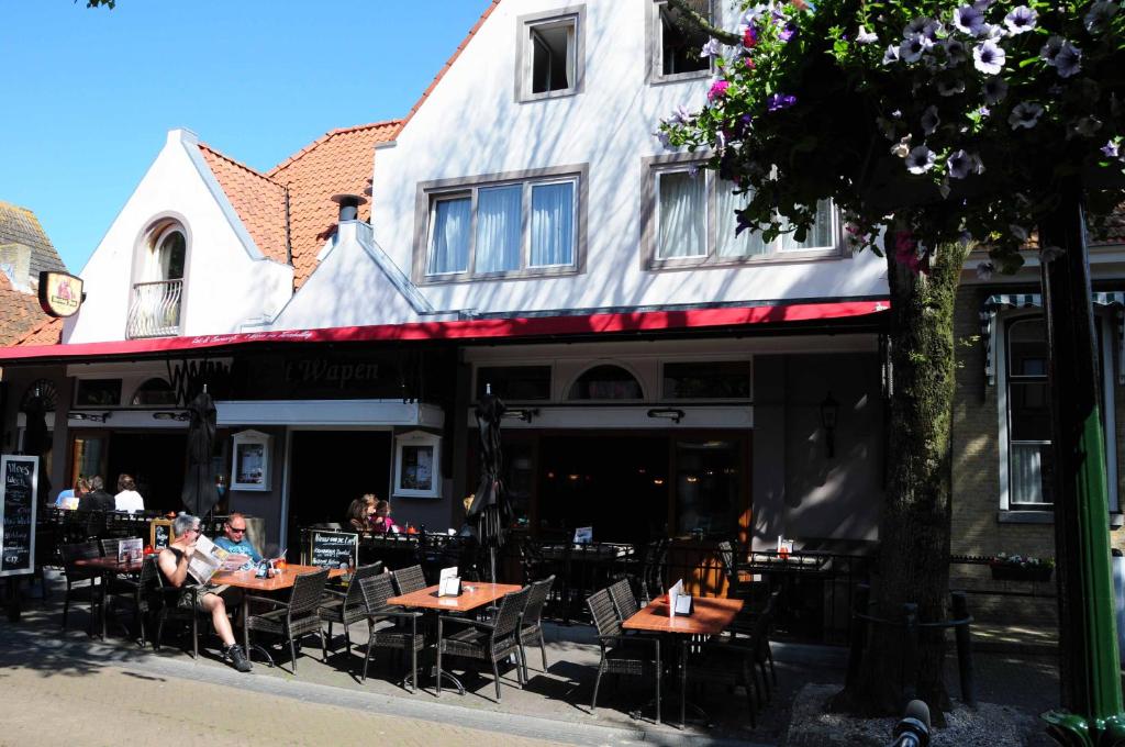 un grupo de personas sentadas en mesas frente a un edificio en `t Wapen van Terschelling en Midsland