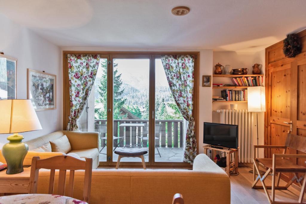 a living room with a couch and a tv and a window at Chesa Alvra - Celerina in Celerina