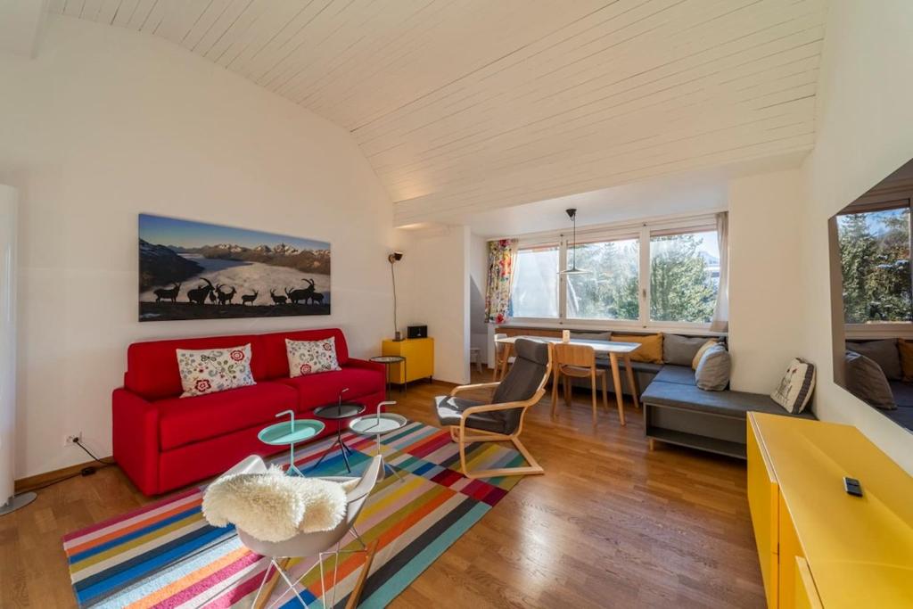 a living room with a red couch and a table at Chesa Nair - Surlej in Surlej