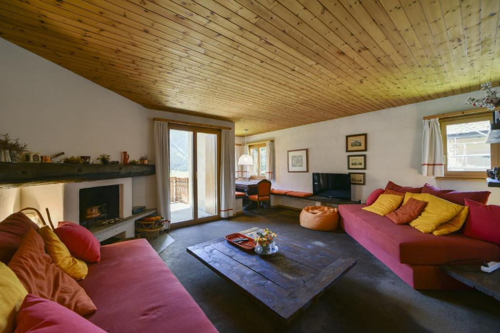 a living room with a pink couch and a fireplace at Chesa Bursella - Madulain in Madulain