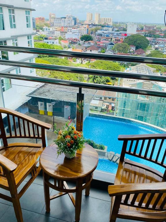 a balcony with two chairs and a table with flowers on it at EM Suite Homestay Dperdana Apartment Kota Bharu in Kota Bharu