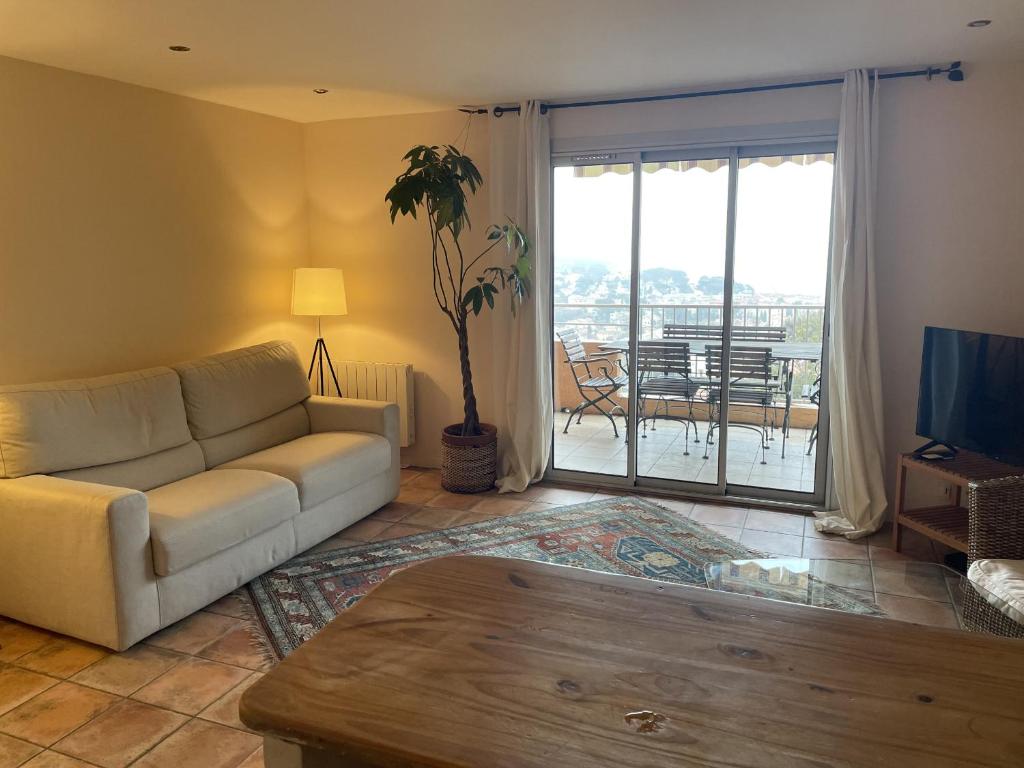 salon z kanapą i stołem w obiekcie 2-room apartment with a magnificent view of the sea, in carqueiranne in the var, 12km from the isles de porquerolles boarding port – 2/4 people w mieście Carqueiranne