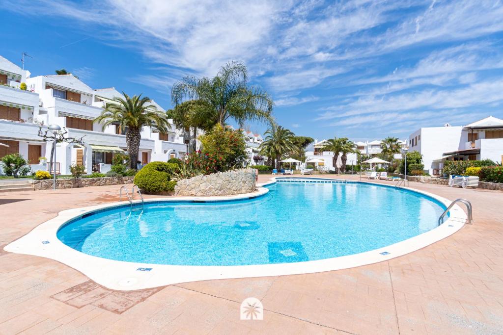 a swimming pool in a resort with palm trees at Mediterranean Way - Punta Prima in La Pineda