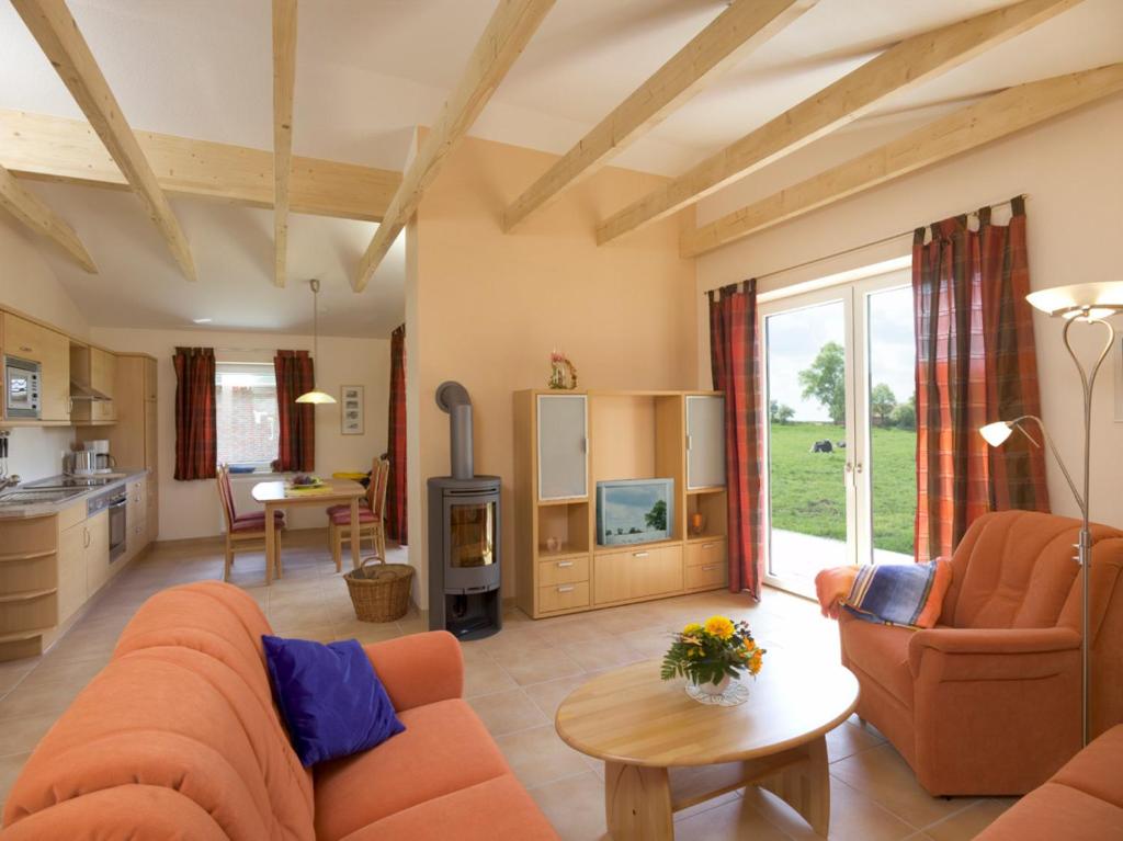 a living room with orange furniture and a kitchen at Bauernhof Sauer - Heuerhus in Varel