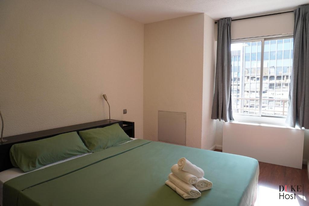 a bedroom with a green bed with towels on it at Chamartin Centro Norte Apartment in Madrid