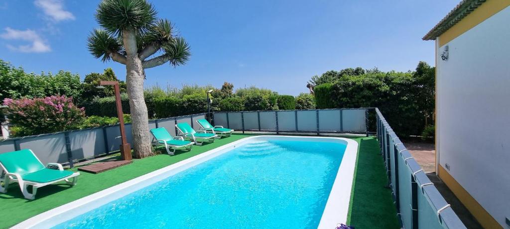a swimming pool with chaise lounge chairs and a fence at Quinta São José da Relva in Ponta Delgada