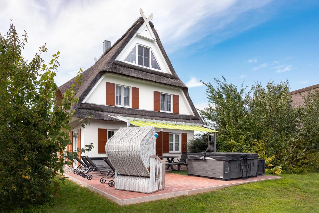 a house with a thatched roof with a grill at C 6 Reethaus Strandkorb mit Außenwhirlpool und Sauna in Gramkow