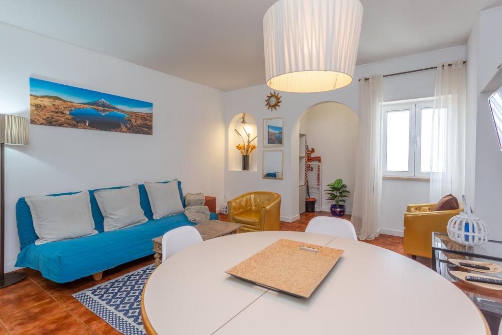 Una sala de estar con una mesa y un sofá azul. en BeGuest Caparica Beach & Surf, en Costa da Caparica