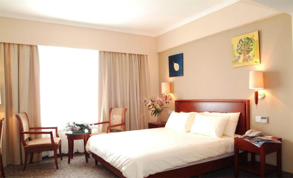 ein Hotelzimmer mit einem Bett, Stühlen und einem Fenster in der Unterkunft GreenTree Inn Hebei Tangshan Leting East Maoyuan Street Third Middle School Business Hotel in Laoting