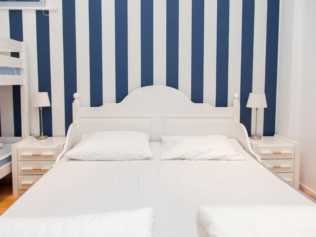 een wit bed in een kamer met blauwe en witte strepen bij Appartementen Zandvoort in Zandvoort
