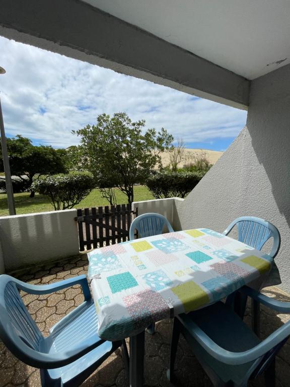 - une table et des chaises avec une couette sur la terrasse dans l'établissement Réf 434 Seignosse océan, appartement classé 2 étoiles, accès direct à l'océan et place de parking privée, 4 personnes, à Seignosse